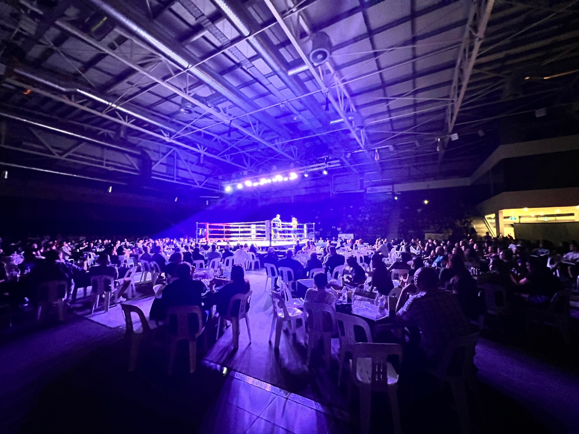 Ringside tables and a packed crowd under blue lights at King of the Ring